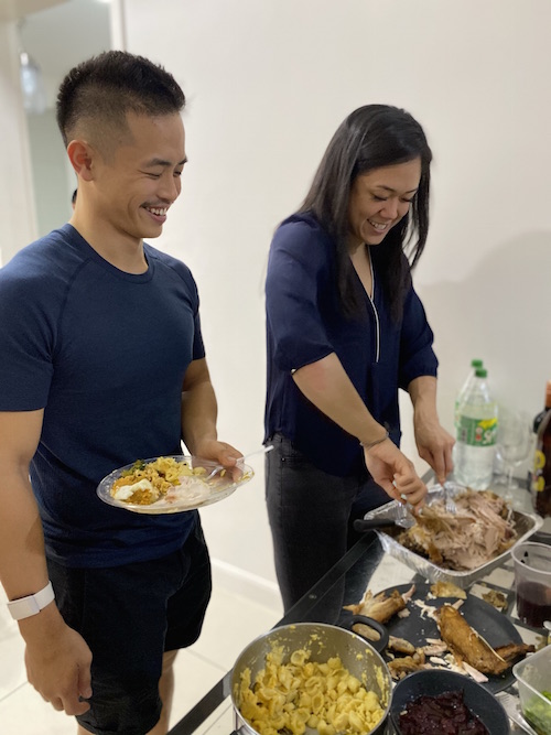 Young woman carving a turkey while young man watches
