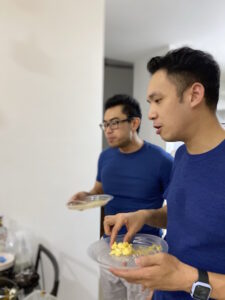 Two men in blue with plates of food