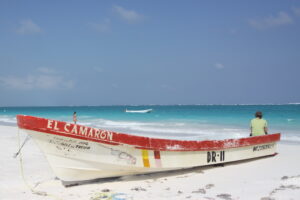white and red fishing boat on a white sandy beach