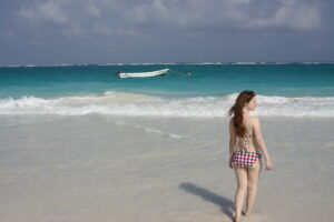 girl in bikini walks into blue water at beach