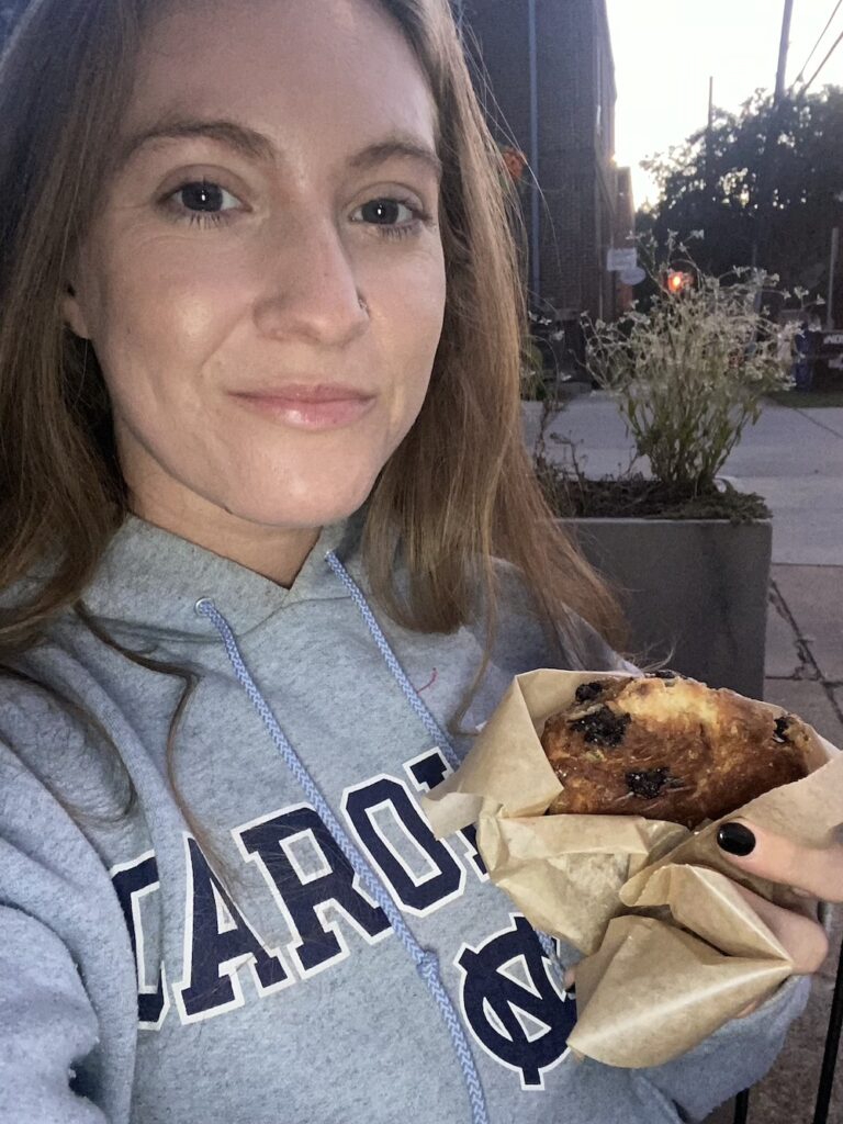 Girl in Sweatshirt holds up a scone