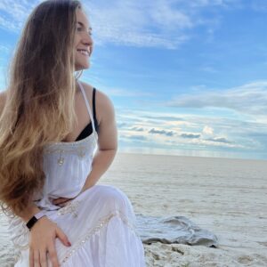 Girl in white on beach smiles into distance