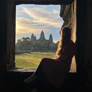 Girl sits in window looking out at Angkor Wat