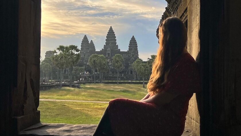Girl sits in window looking out at Angkor Wat